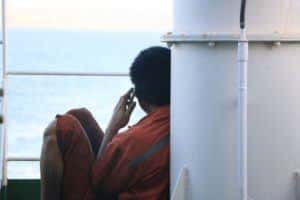 Seafarer sitting aboard, calling his family
