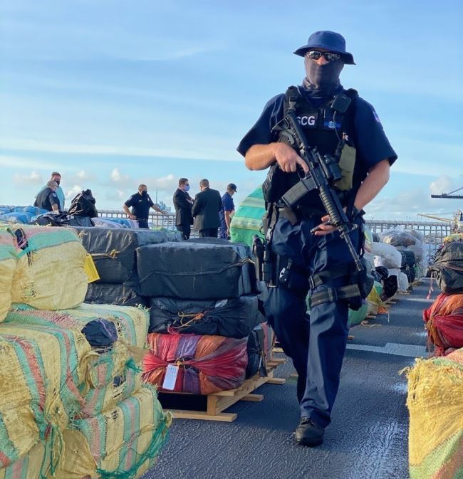 Coast Guard Petty Officer 2nd Class Jonathan Ayers guards approximately 11,500 pounds of interdicted cocaine and approximately 17,000 pounds of interdicted marijuana