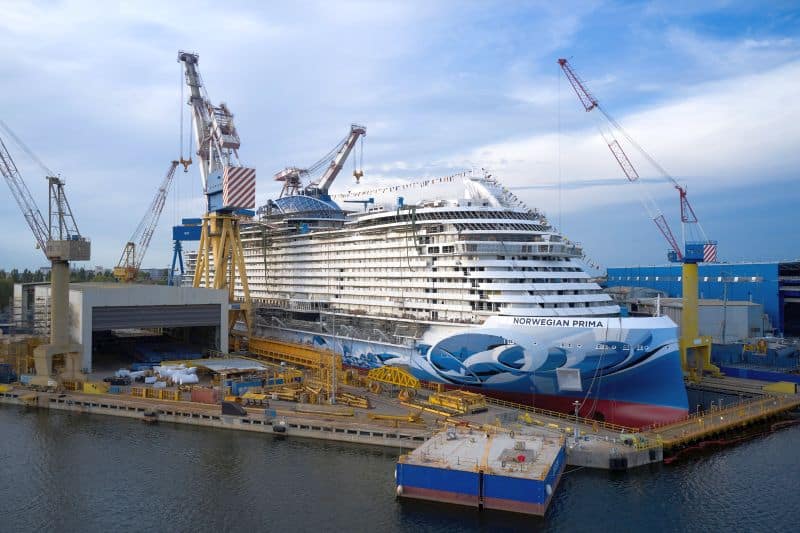 Cruise ship Norwegian Prima under construction with tall cranes all around it