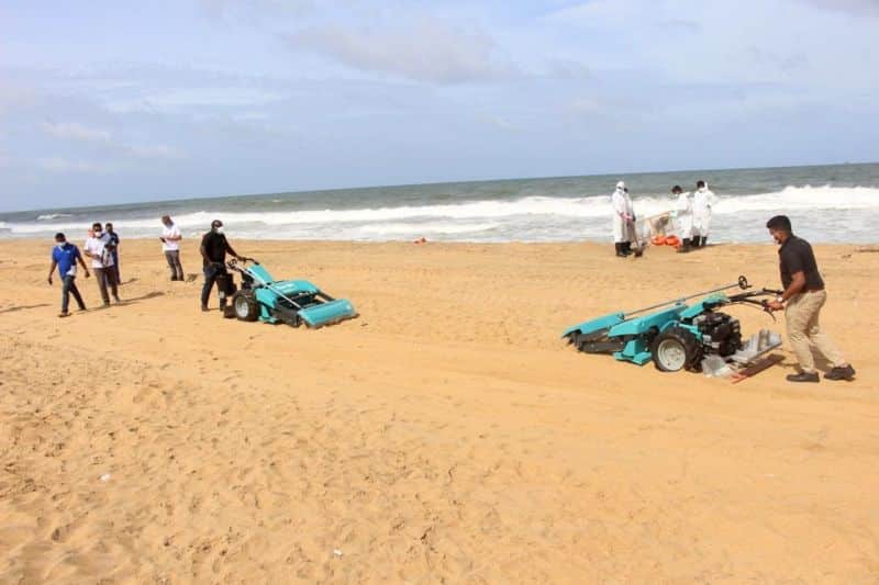 workers using the machines for cleanup of the beach