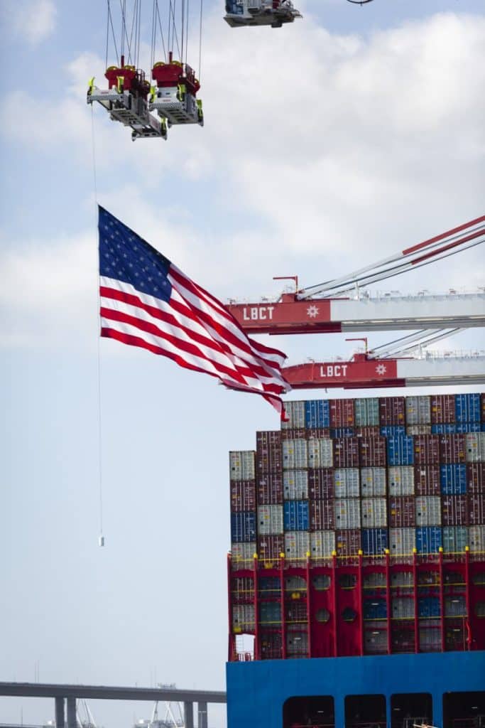 The U.S. flag flies with a cargo vessel in the background. Long Beach Container Terminal Completion Celebration on Friday, Aug. 20, 2021, held at LBCT at Middle Harbor.